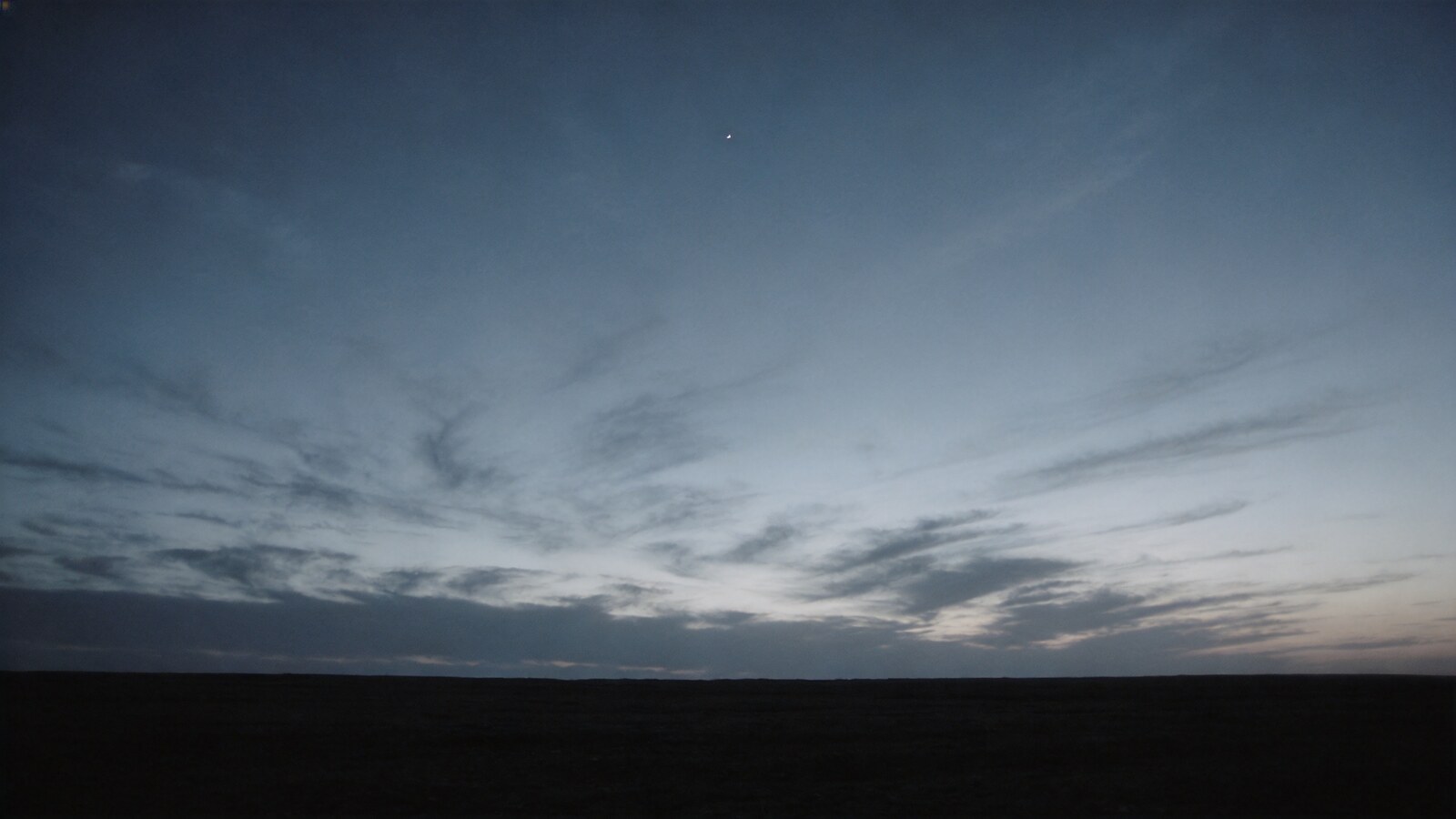 Atmospheric image: a wide, clearing twilight sky over an open dark horizon, a single star still visible — symbolic of a question that stays open yet is thought through clearly.