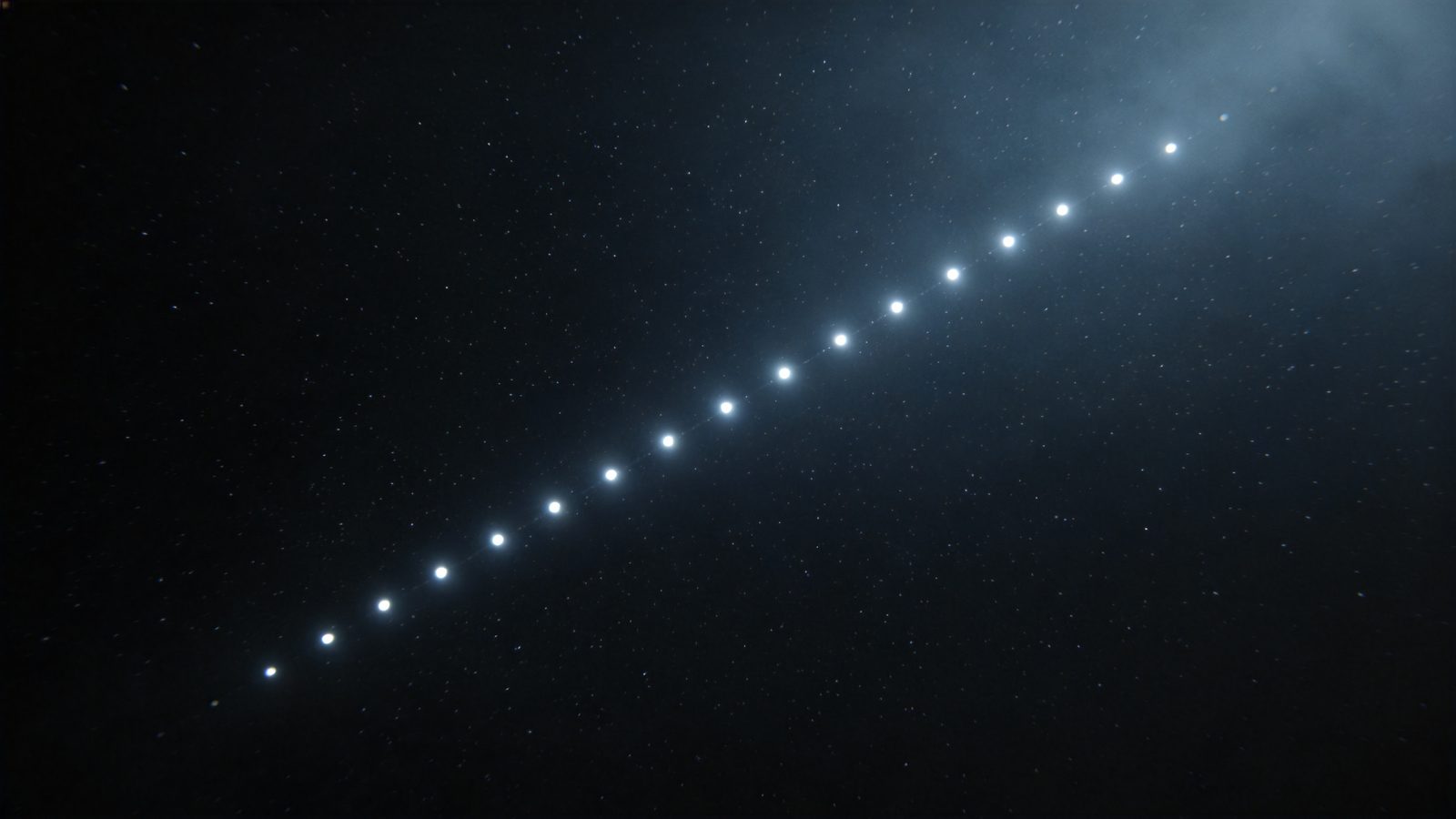 Illustration: a pearl-string chain of evenly spaced bright dots crosses the dark night sky — the typical pattern of freshly launched Starlink satellites.